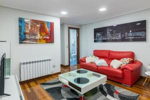 a living room with a red couch and a table at Piso con piscina in Bádames