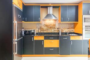 a kitchen with black and orange cabinets at Piso con piscina in Bádames