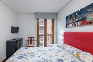 a bedroom with a bed with a red headboard at Piso con piscina in Bádames +18 photos