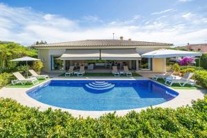 a swimming pool in a yard with chairs and umbrellas at Villa Bellviure Luxury in Palma in Marratxí 