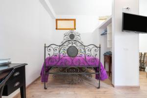 a purple bed in a room with a tv at Alla Marina Monolocale Deluxe in Cagliari