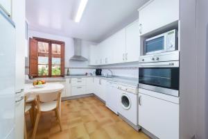 a white kitchen with a table and a microwave at Can Guixa in Sóller