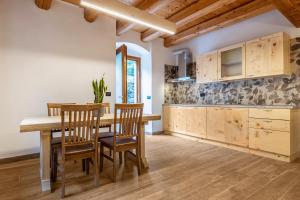 a kitchen with wooden cabinets and a wooden table and chairs at Casa al Mulino 2 in Tenno