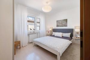 a white bedroom with a bed and a window at Ferienwohnung Bachem mit Balkon in Bad Neuenahr-Ahrweiler