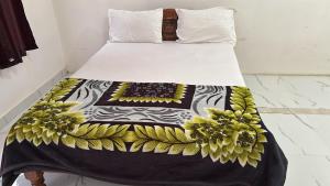 a bed with a black and yellow blanket on it at Subhiksha Rooms in Bellūru