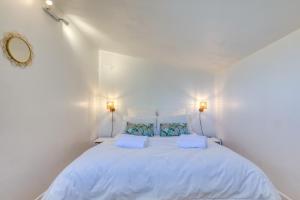 a white bedroom with a large bed with two lamps at Mas des Cypres - Mazet 9 in Saintes-Maries-de-la-Mer