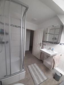 a white bathroom with a shower and a sink at Meeresleuchten 2 in Emden