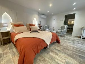 a bedroom with a large bed with an orange blanket at La Colombière in Salviac