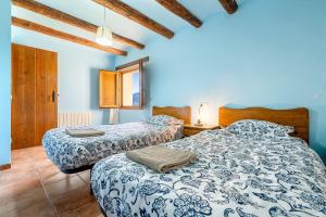 two beds in a room with blue walls and wooden ceilings at La Sala in Peñarroya de Tastavins