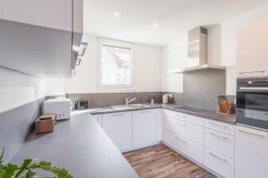 a white kitchen with white cabinets and a sink at Ferienhaus Am Rösslewald in Breitnau
