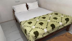 a bed with a polka dot blanket and pillows at Subhiksha Rooms in Bellūru