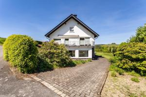 a white house with a balcony and a brick driveway at Ferienwohnung Auszeit Sauerland in Meinerzhagen