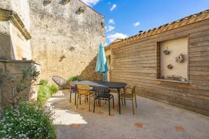 a patio with a table and chairs and an umbrella at Isatis in Mortagne-sur-Gironde