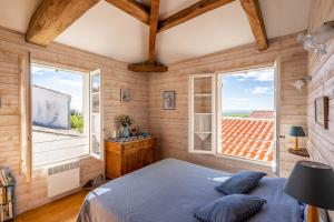 a bedroom with a bed and two windows at Isatis in Mortagne-sur-Gironde