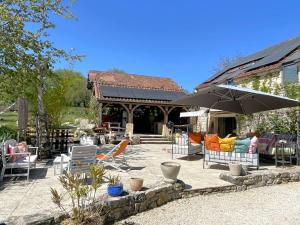 a patio with a bunch of chairs and an umbrella at La Colombière in Salviac