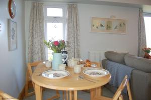 a living room with a wooden table with plates on it at Bryn Rhedyn Fairbourne in Fairbourne