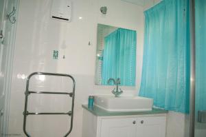 a bathroom with a sink and a blue shower curtain at Bryn Rhedyn Fairbourne in Fairbourne +60 photos