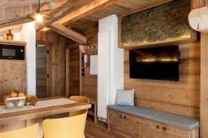a dining room with a table and a tv at Alpine Mood Apartments in Falcade