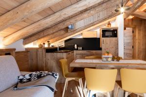 a kitchen with wooden walls and yellow chairs at Alpine Mood Apartments in Falcade