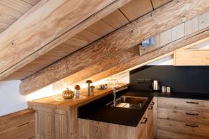 a kitchen with a sink and a wooden ceiling at Alpine Mood Apartments in Falcade +143 photos