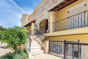 a yellow house with stairs and a gate at Villa Konstantina Lulas Penthouse in Petrití