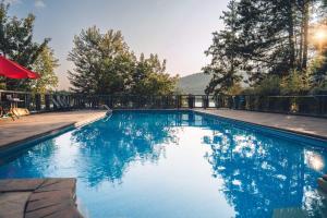 a blue swimming pool with a fence and trees at SpaHaus #128 in Lac-Superieur