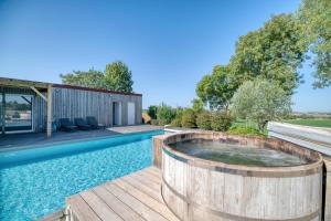 a hot tub on a deck next to a swimming pool at Villa Virginie gite 2 in Faudoas
