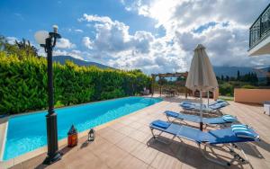 a pool with lounge chairs and an umbrella at Sami Beach Villas Thalia in Sami