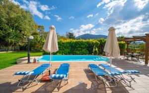a swimming pool with blue chairs and umbrellas at Sami Beach Villas Thalia in Sami