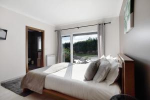 a bedroom with a large bed and a large window at Villa Mila Piscina e Jacuzzi in Salir de Matos +33 photos