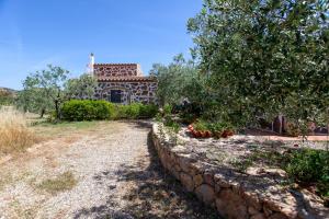 a stone wall in front of a house with a tree at Sa Domedda in Orosei