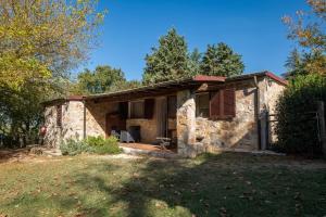 a small stone house with a porch in a yard at Volpe in Pitigliano