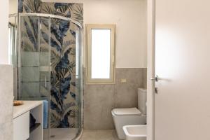 a bathroom with a toilet and a glass shower at Sunset Dimora in Siculiana Marina +27 photos