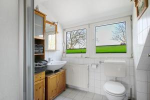 a bathroom with a toilet and a sink and two windows at Ferienwohnung Fraulund in Rügge +16 photos