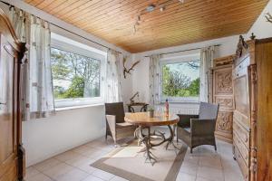 a dining room with a table and chairs and two windows at Ferienwohnung Fraulund in Rügge