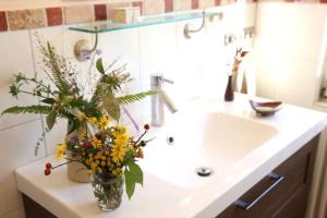 a white sink with a vase with flowers on it at Luise Im Künstlerhaus in Langmühle +19 photos