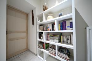 a white book shelf filled with books next to a door at La maison Poulogne in Capvern