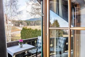 a balcony with a table and chairs and a window at Haus Alpenquelle Seeblick in Bad Kohlgrub