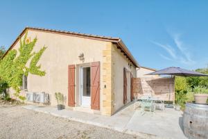 a small house with a table and an umbrella at Le Refuge des Vignes in Lamonzie-Saint-Martin