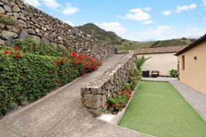 a retaining wall with red flowers and green grass at El Portillo 2 in Buenavista del Norte