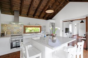 a kitchen with a large white island with white chairs at El Portillo 2 in Buenavista del Norte