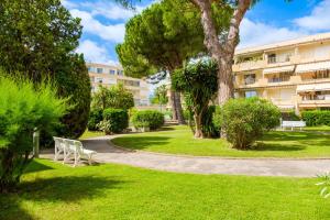 a park with a bench and trees and a building at Des vacances de rêve à Mandelieu in Mandelieu-La Napoule