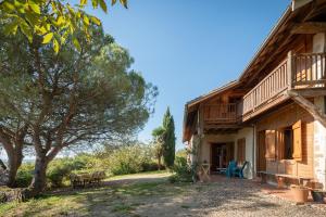 a log house with a porch and a tree at Maison de vacances La Toumet in Malabat