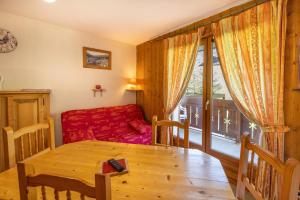 a living room with a table and a red couch at Le jardin des neiges in Praz-sur-Arly