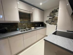 a kitchen with white cabinets and a sink at 4 Studio House Ambleside in Ambleside +2 photos
