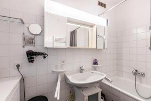 a white bathroom with a sink and a bath tub at Seesucht in Gaienhofen +15 photos