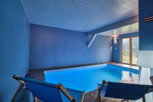 a swimming pool in a house with two chairs and a table at L'Ecrin de Venosc piscine privée in Les Deux Alpes