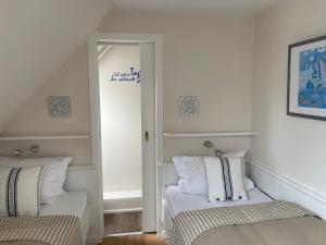 a white room with two beds and a mirror at Meerchenhaus in Wenningstedt