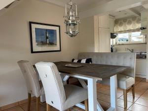 a dining room table with white chairs and a dining room at Meerchenhaus in Wenningstedt