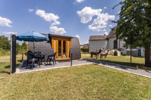 a tiny home with a table and chairs and an umbrella at Campingpod Auf Der Alpakawiese in Arnsberg